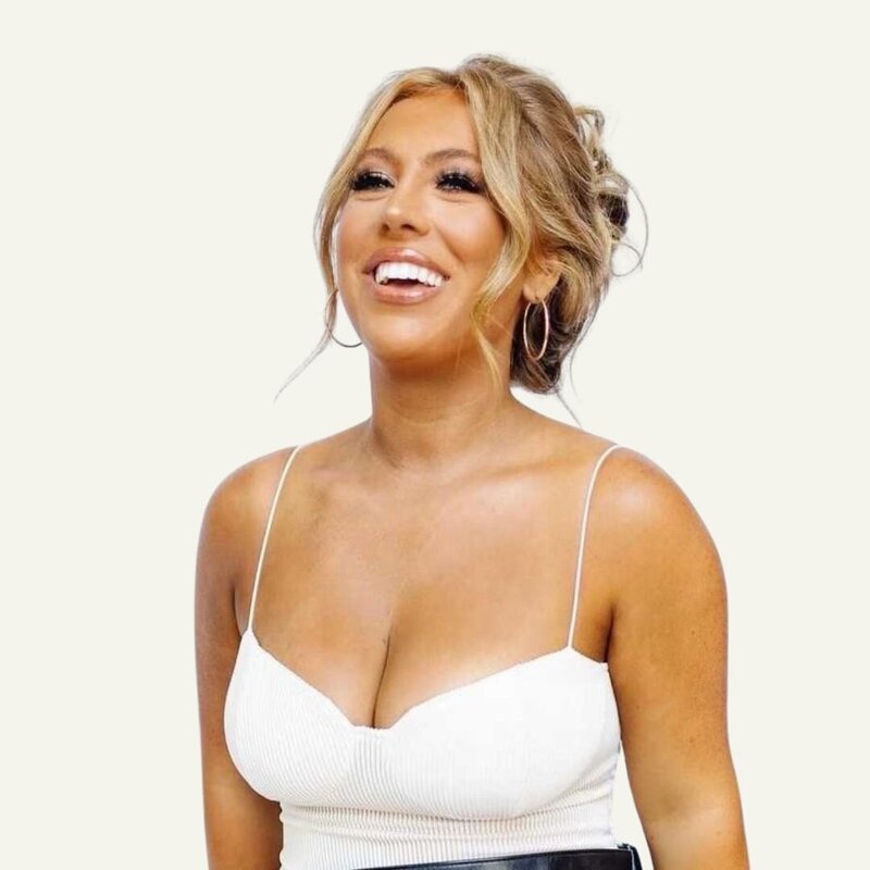 Woman smiling and leaning up against one arm of a chair.