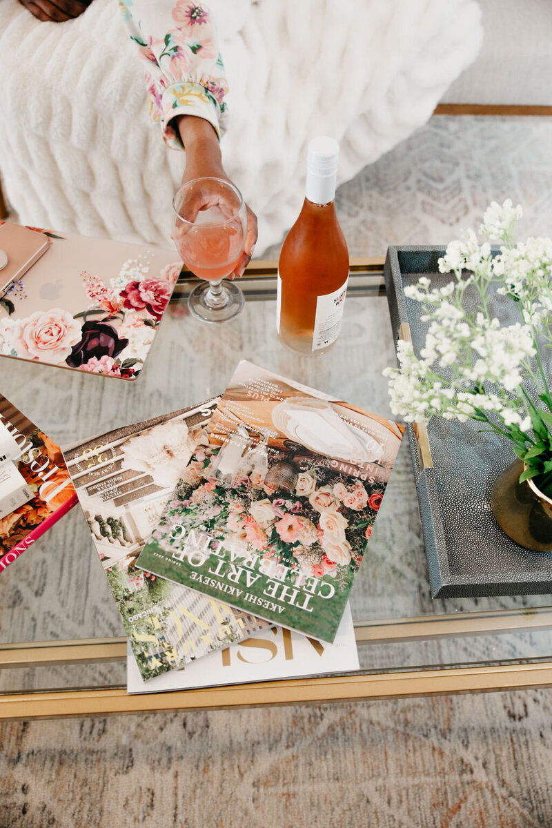 top view of wedding magazines scattered on a glass coffee table and glass of rose wine