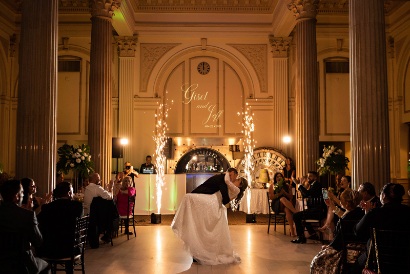 A groom dipping his bride and kissing her in an event space
