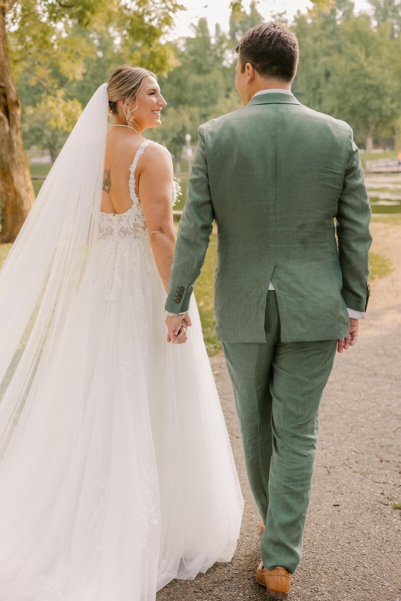 Bride and groom looking at each other and walking away hand in hand.