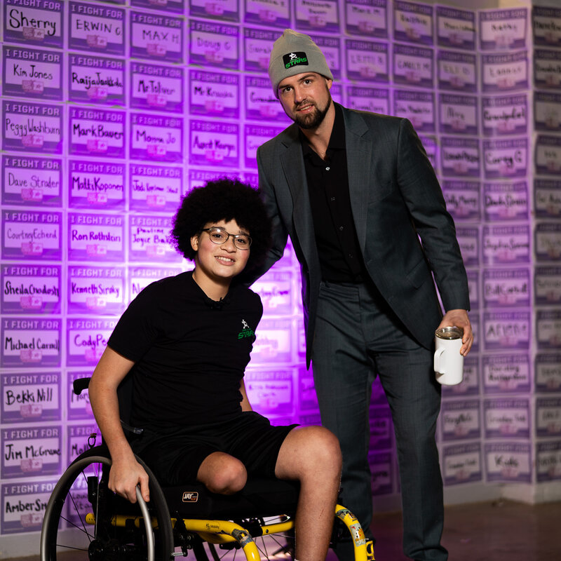 a pediatric cancer warrior and a hockey player taking a picture at a fundraiser