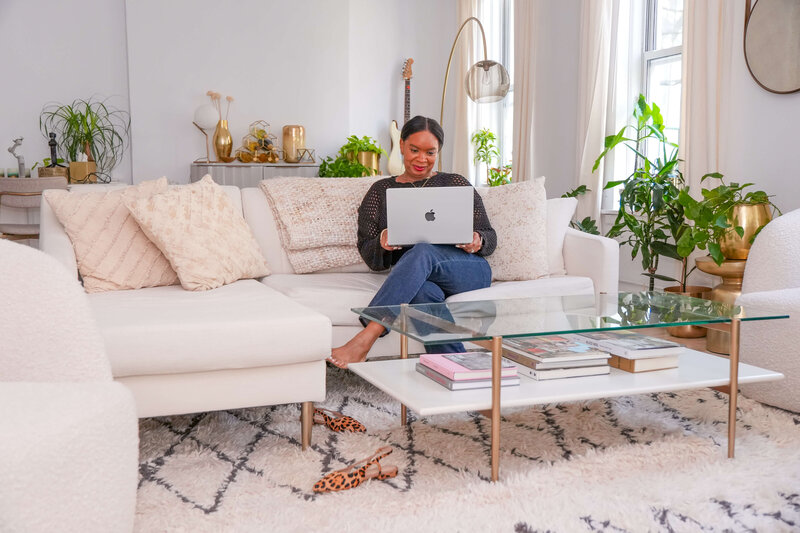 jacinta-gandy-working-on-laptop-in-cozy-living-room-with-plants-and-decor
