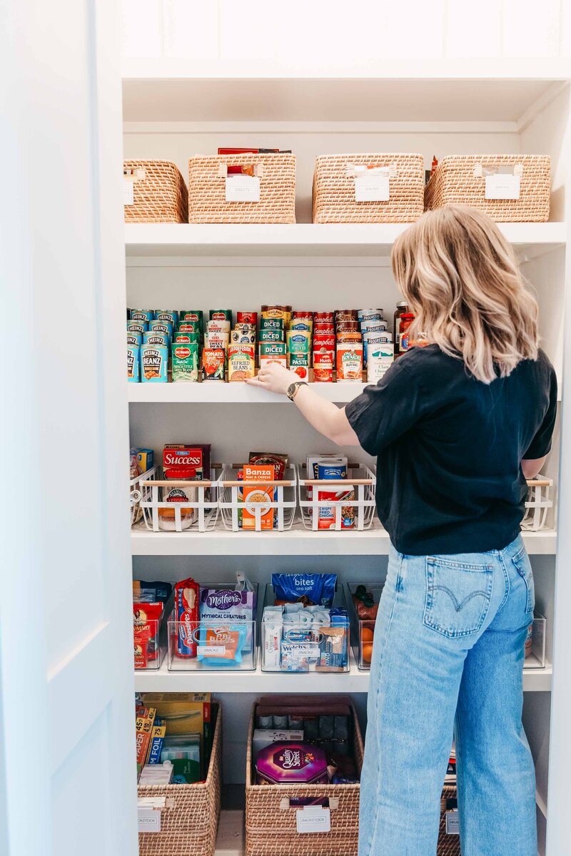 An organizer meticulously placing canned goods in a pantry