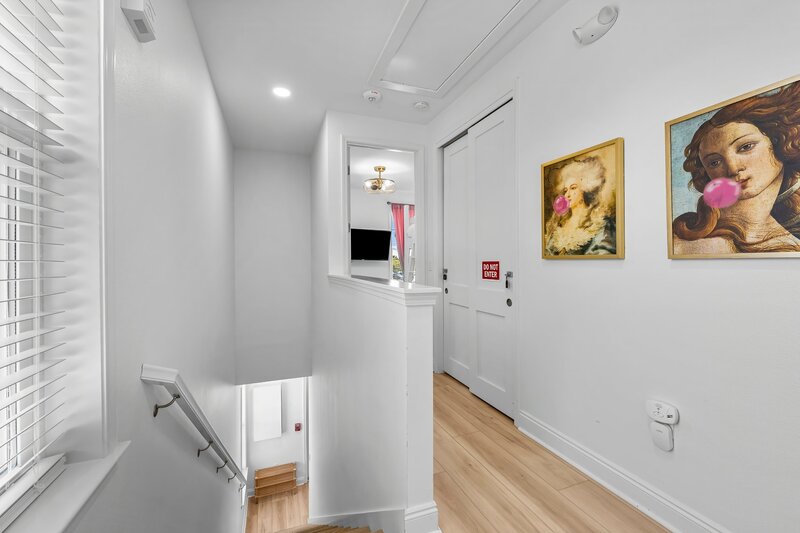 Bright upstairs landing area with cheeky classical artwork, leading to bedrooms—fun and photogenic space in the heart of Panama City Beach.