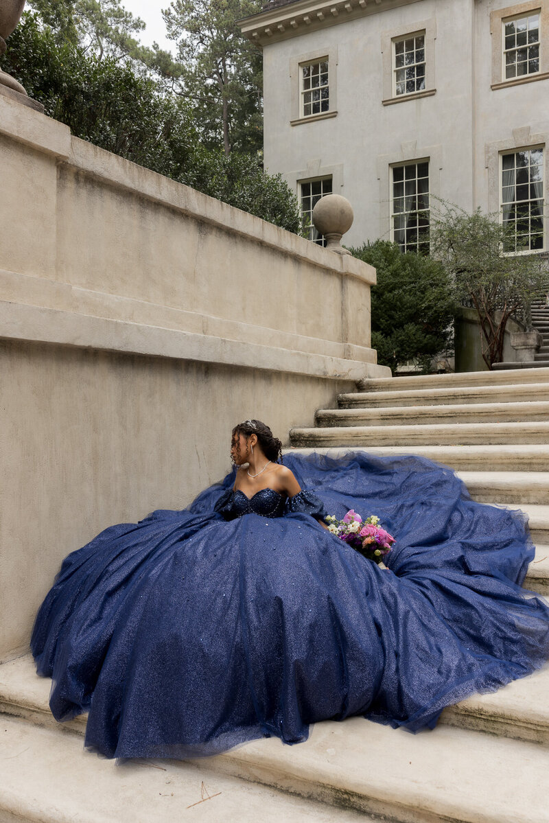 woman in quinceanera dress standing in front of large stone building