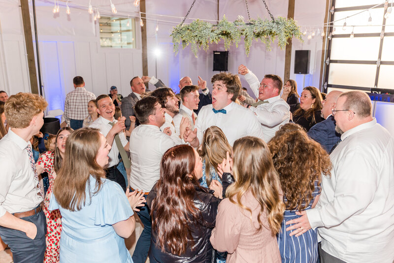 A man in a moment of jump dancing and hooting during a rave style dance party at the reception. 10/10 wish I was there.