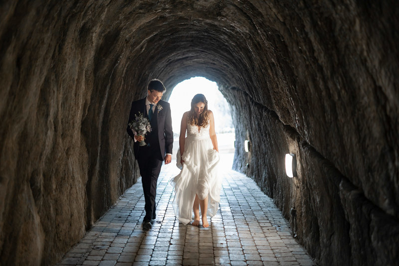 Bride walking with her groom barefoot through Tunnels Beaches wedding venue in Devon