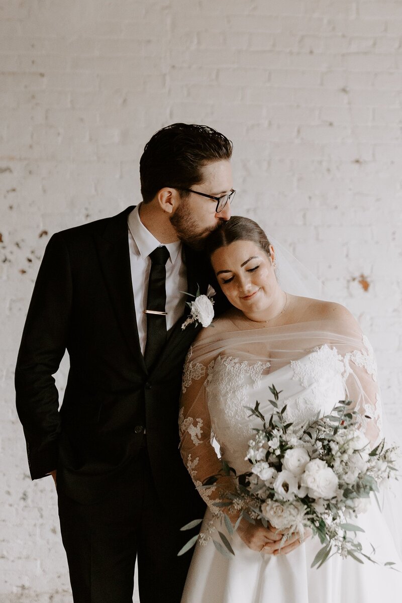 Groom kissing bride on head