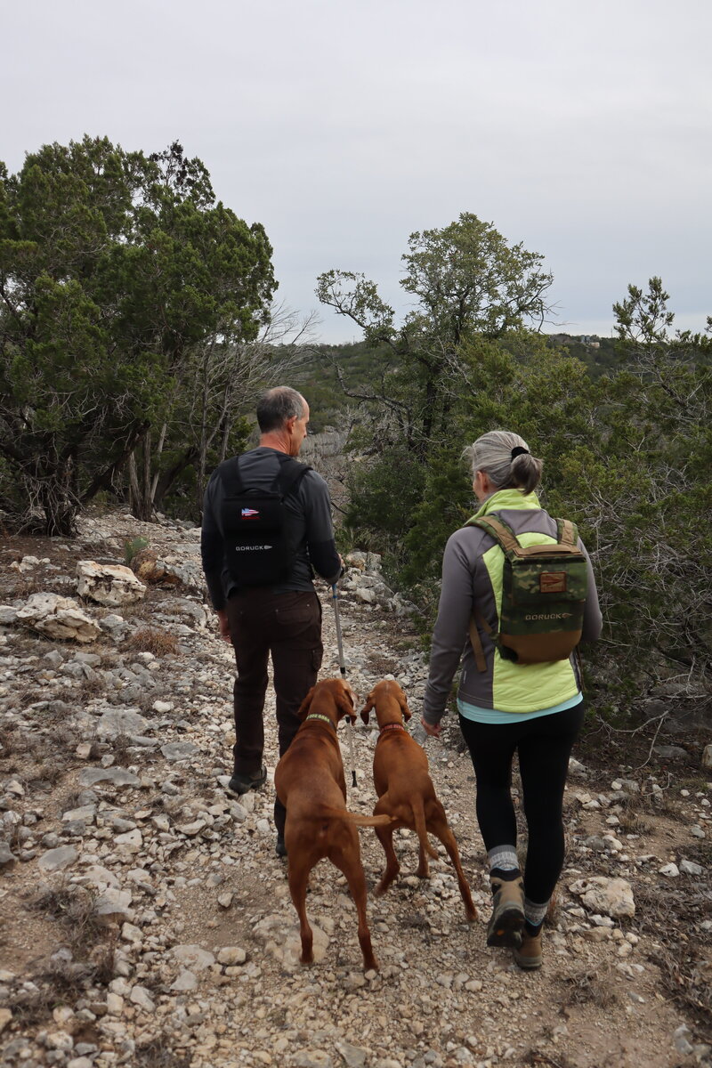 Couple on a rocky hiking trail with two red dogs