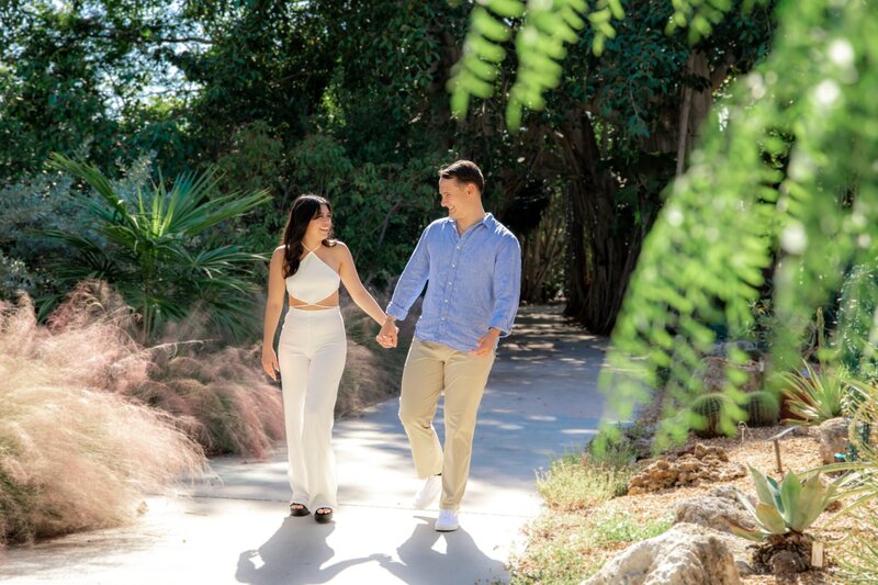 engaged couple holding hands and walking through Selby Gardens