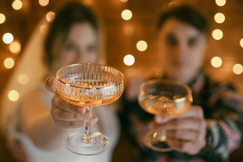 extreme close-up of gold-rimmed, ribbed champagne coups held towards the camera for a CHEERS by the bride and groom.