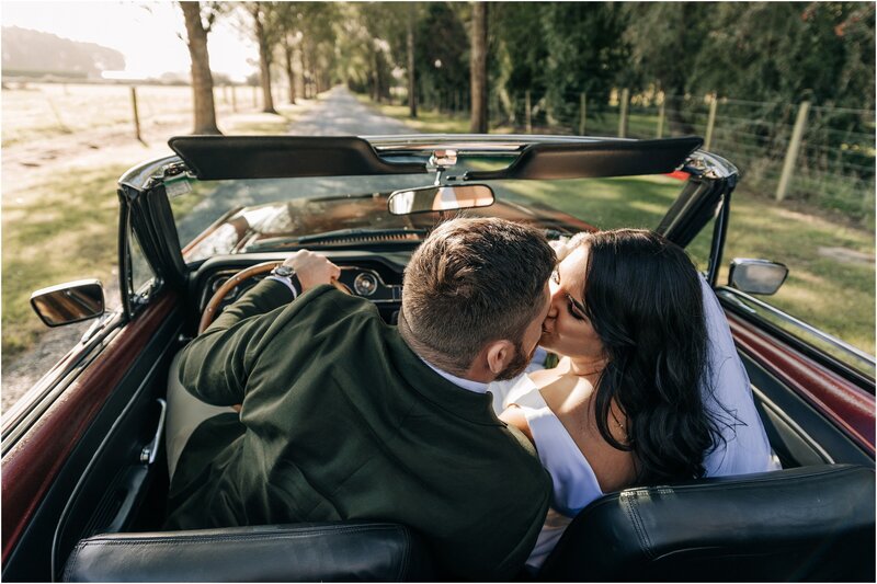 bride and groom kissing in convertible car on country road candid moment in ohoka christchurch nz