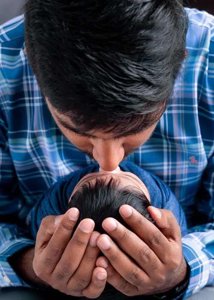 father-kissing-newborn-baby-close-up