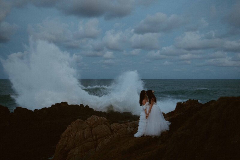two brides on top of a cliff overlooking the rugged ocean byron bay australia  lgbtq+ally  friendly