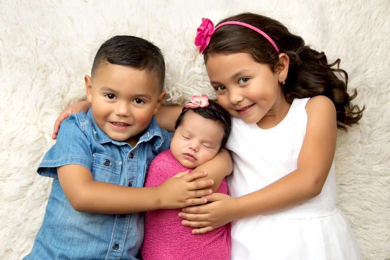 siblings holding baby girl