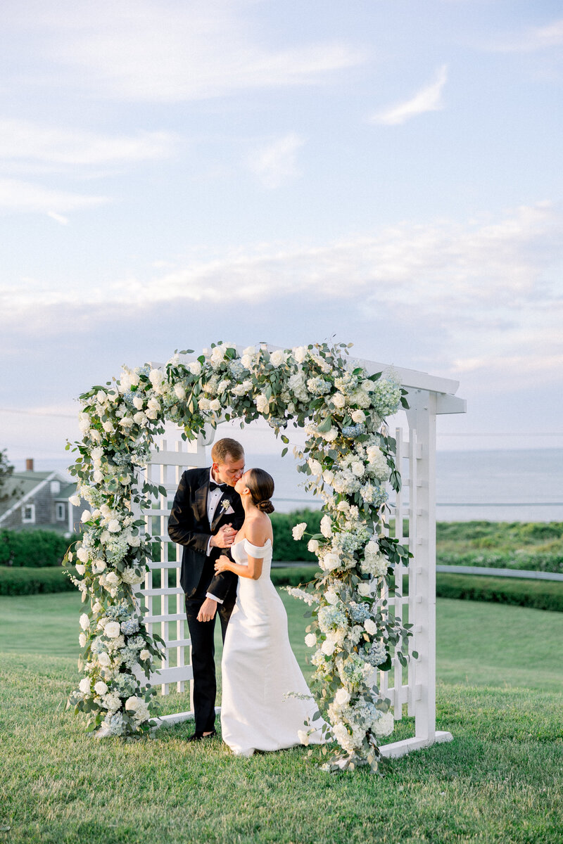 Bride and groom share first kiss under floral arch at Spring House wedding