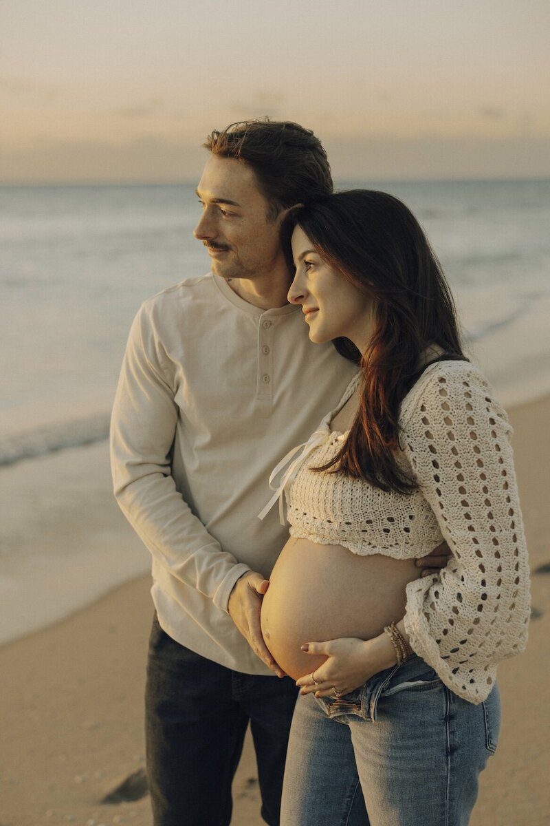 couple poses on beach in south florida for maternity photos
