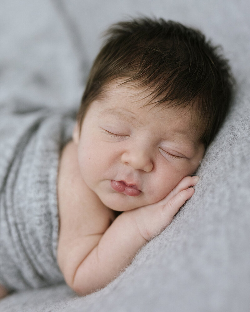 newborn baby boy with lots of hair, sleeping with a grey blanket, Perth newborn in home session
