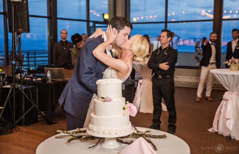 Couple kisses after cutting their cake at their Champagne powder room reception in Steamboat Springs