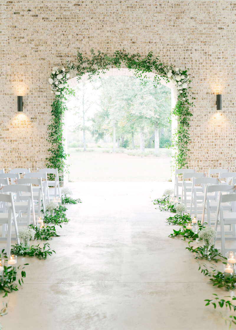 beautiful flower arch and white chairs with floral decorations for wedding reception