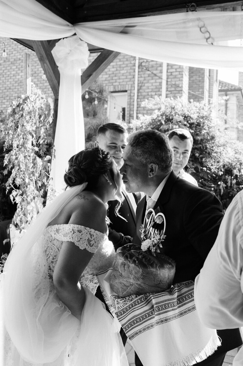 Peruvian bride and her father enjoying Ukranian bread exchange wedding tradition.