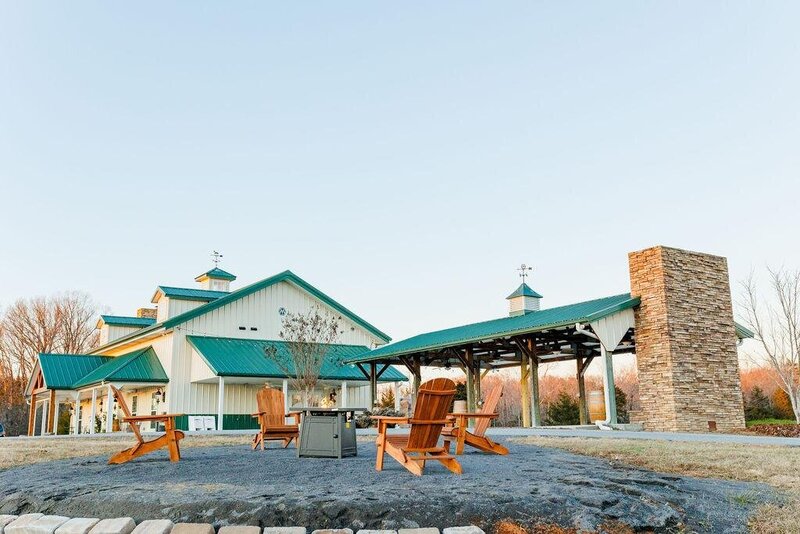 The green-roofed exterior of Willow and Stone Events, featuring a cozy firepit with Adirondack chairs, perfect for weddings and celebrations near Charlotte, NC.