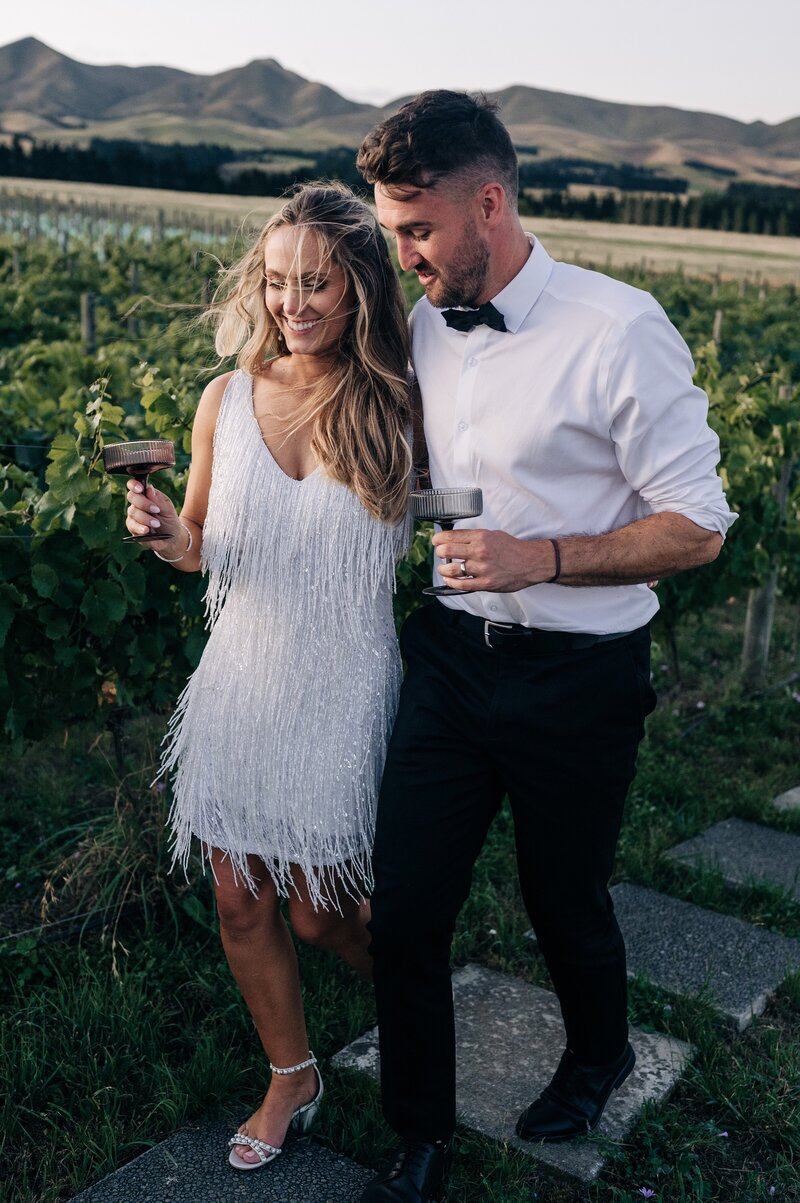 bride in sparkly beaded mini white reception dress in a vineyard at their christchurch wedding