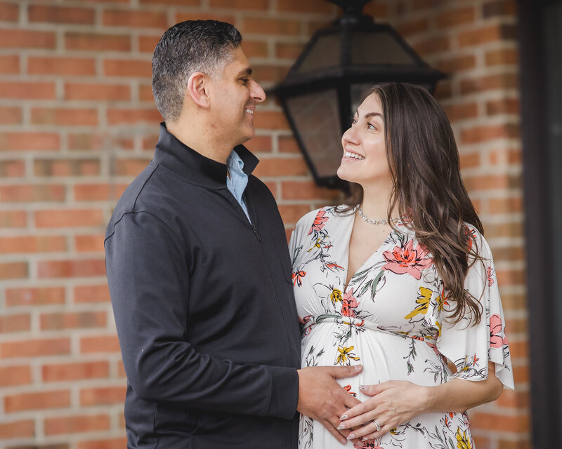 An expecting couple looks into each others' eyes