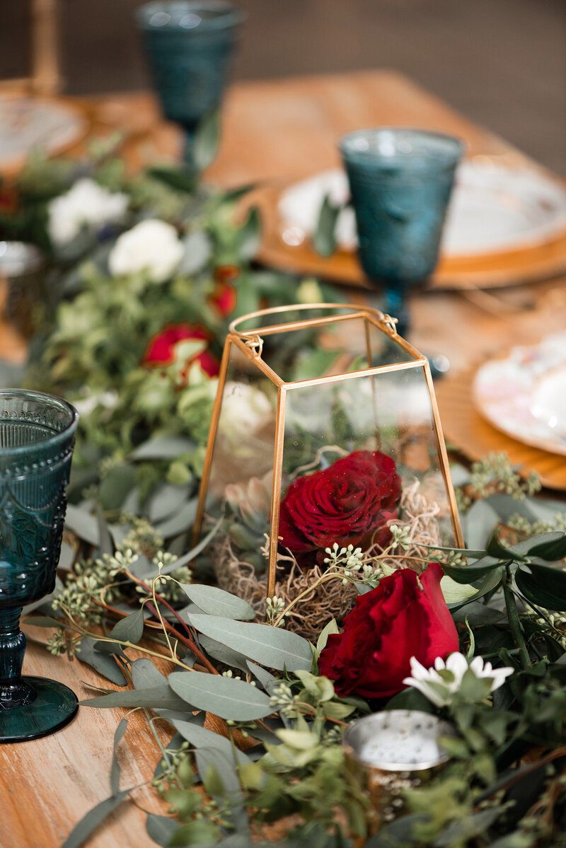 Red roses paired with gold and teal decor for centerpieces