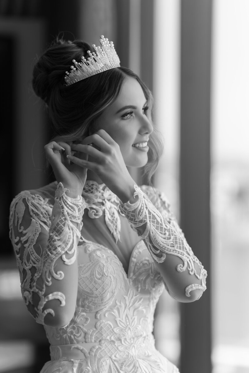 bride with high upstyle and crown placing her earrings in