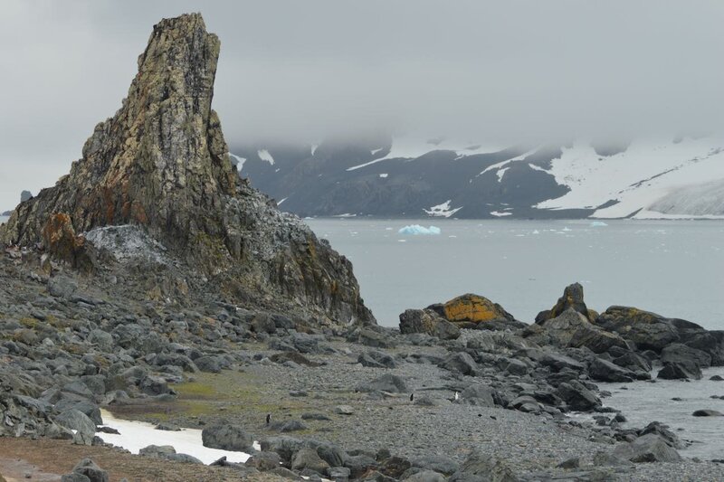 Volcanic remnants in Antarctica, with misty mountains and a bay behind. 