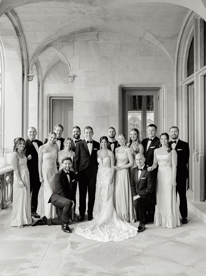 Black and white photo of a wedding party smiling at the camera 