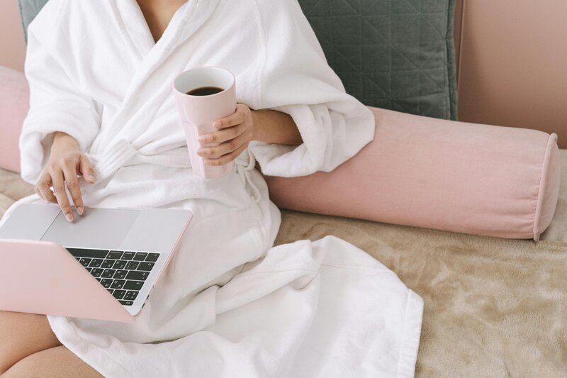 woman relaxing in bed with laptop and coffee