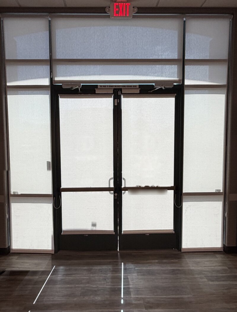Commercial solar roller shades on storefront door sidelights and transom windows in Las Vegas