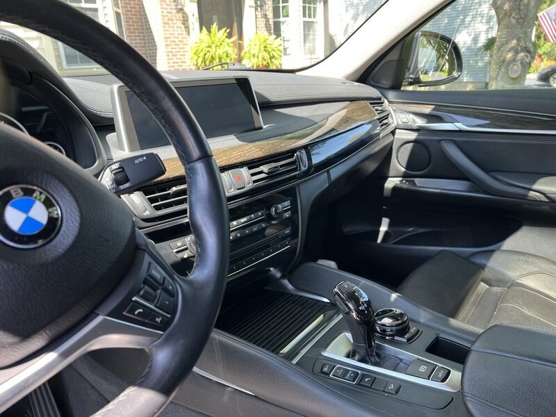 Interior view of a BMW X3 SUV, showcasing the dashboard, steering wheel with the BMW logo, infotainment system, and leather seats. This image highlights the clean and well-maintained interior, likely a result of professional interior car detailing services at Superstar Auto Spa in Ozone Park, NY. 