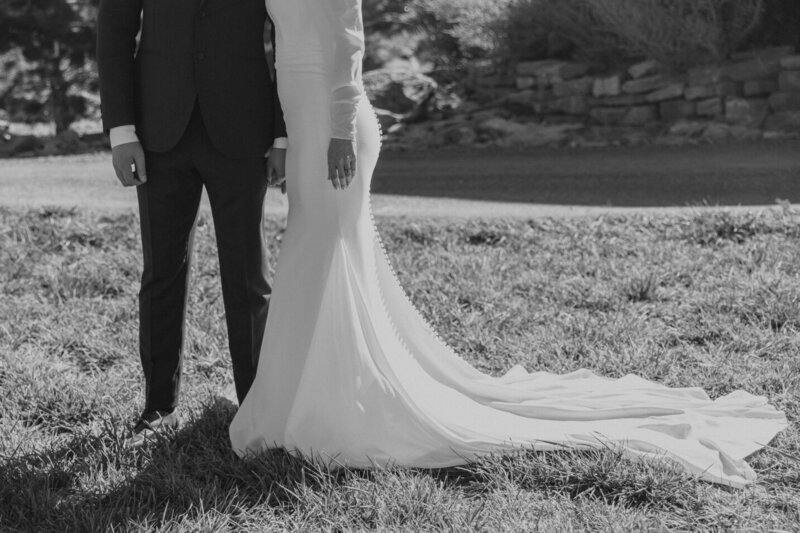 A bride and groom on their wedding day from the chest down so you can't see their faces. The timeless photo was taken during their Elopement and is black and white.