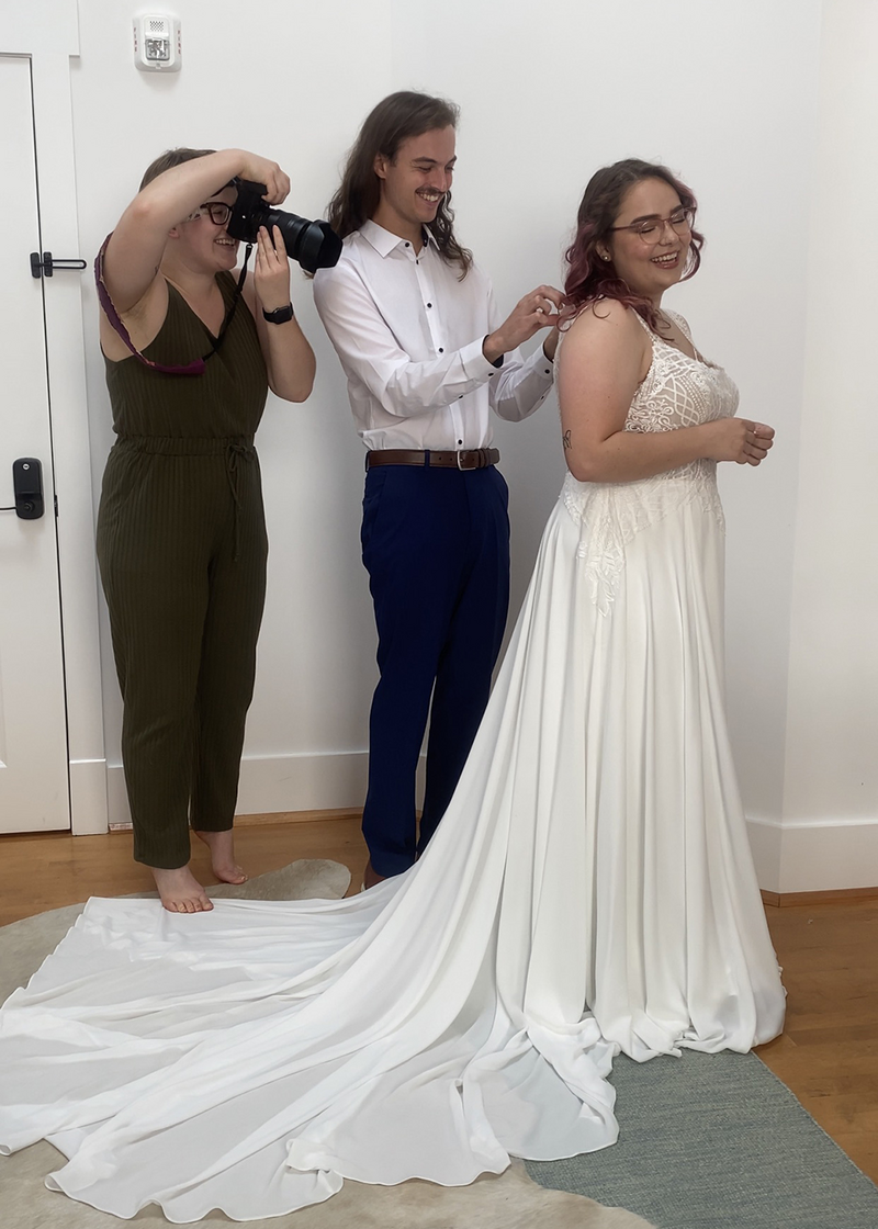 A Virginia elopement photographer takes pictures of a groom helping button the bride's dress during their elopement in Roanoke, Virginia.