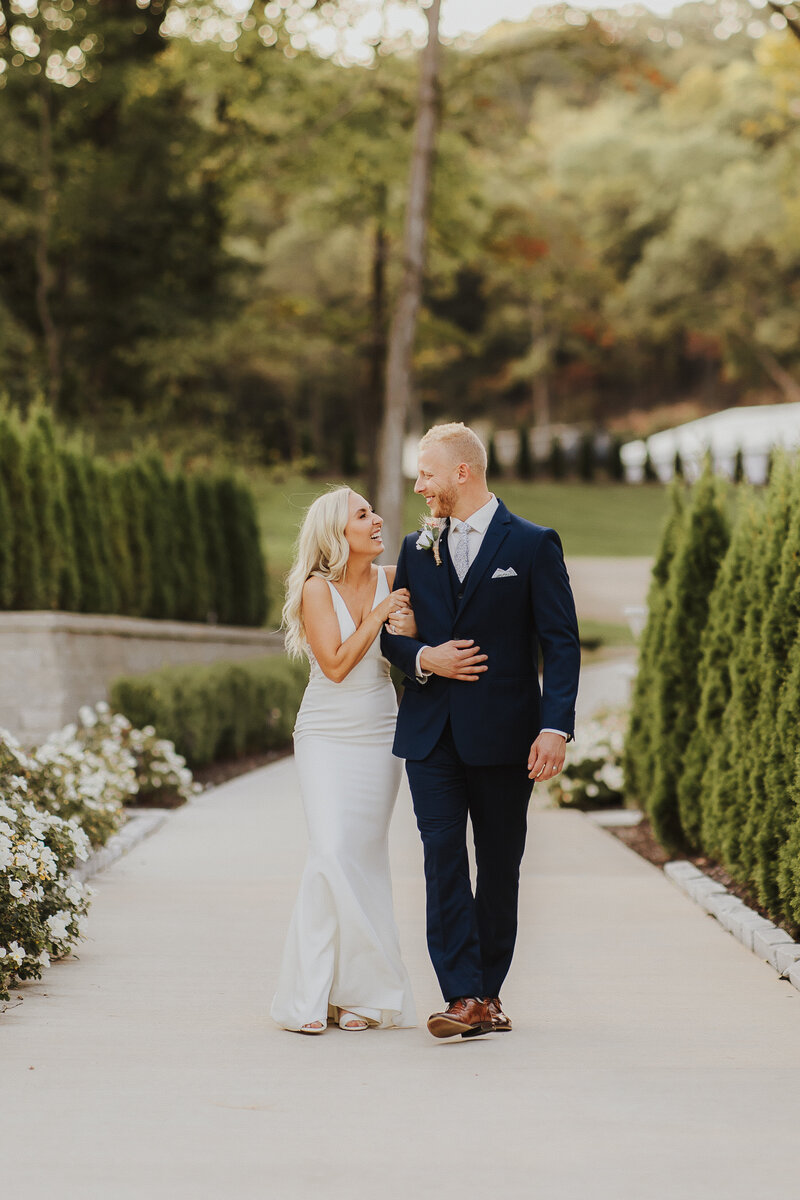 elegant bride and groom walk through garden at knotting hills