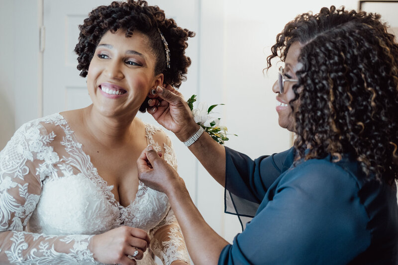 A mother dressed in blue helps her daughter put on earrings