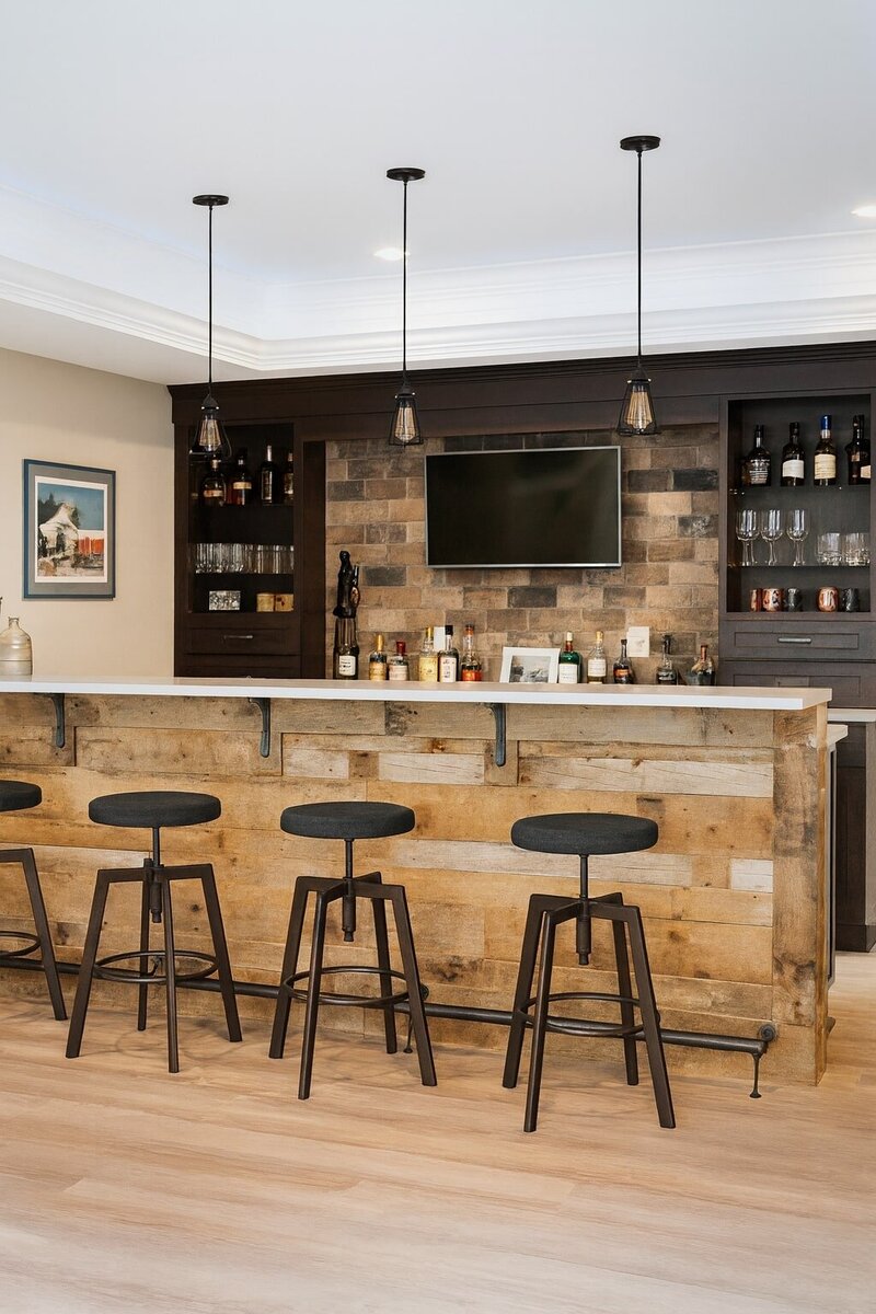 Basement renovation featuring a rustic home bar with wood accents, pendant lighting, and built-in shelving.