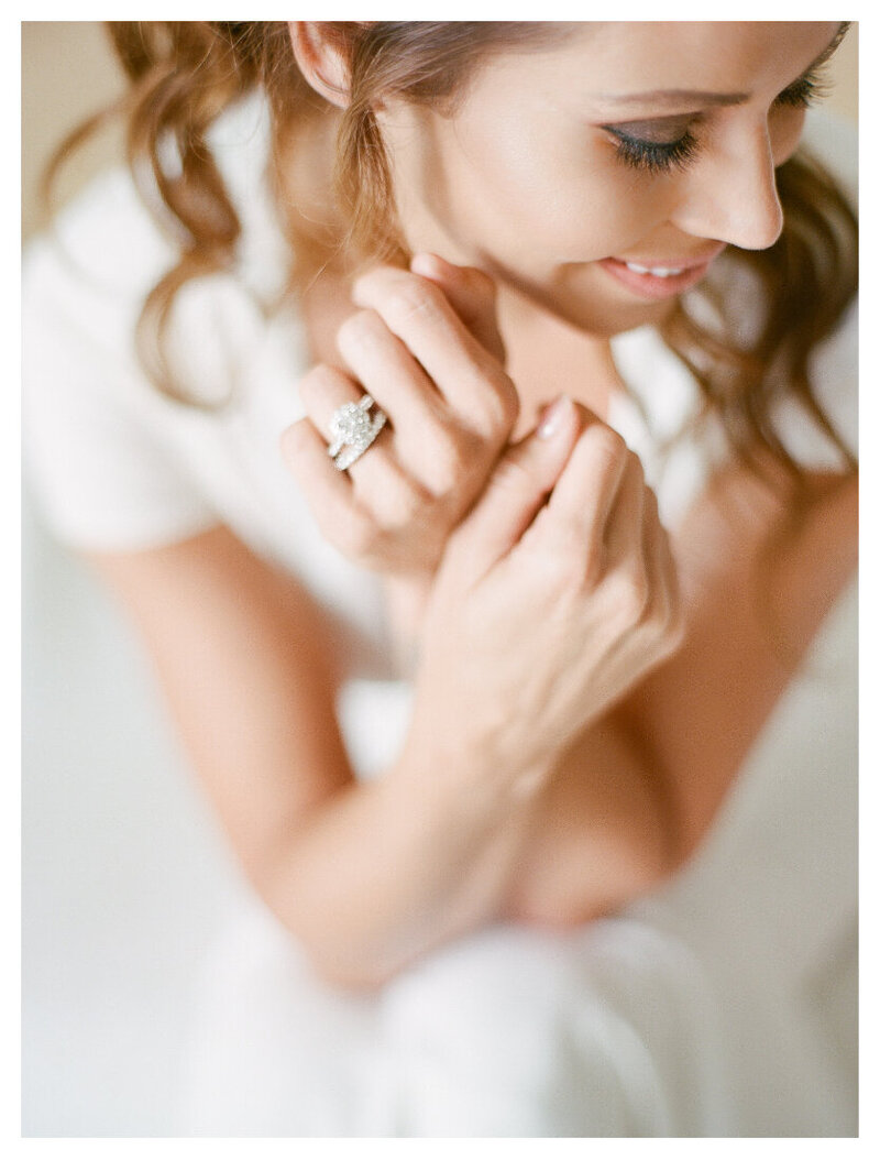 Closeup of a bride smiling and holding her hands up with diamond engagement ring