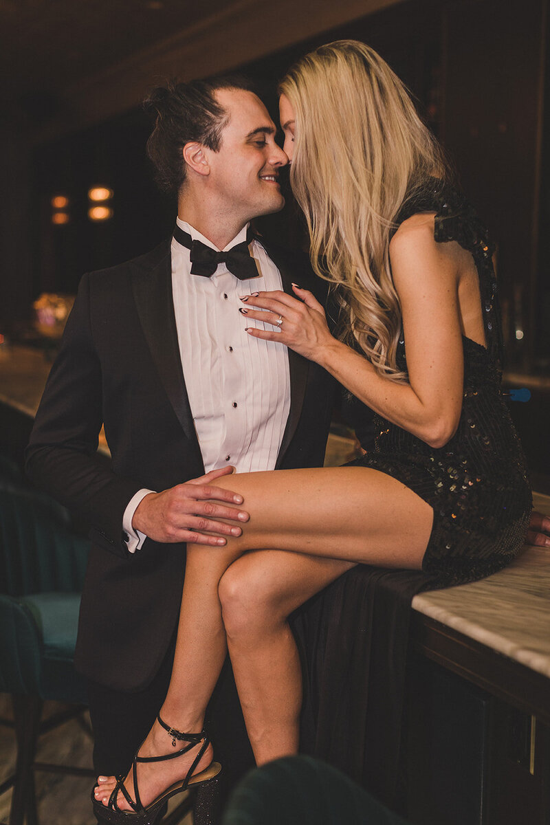 couple embraces on bar for las vegas engagement photos