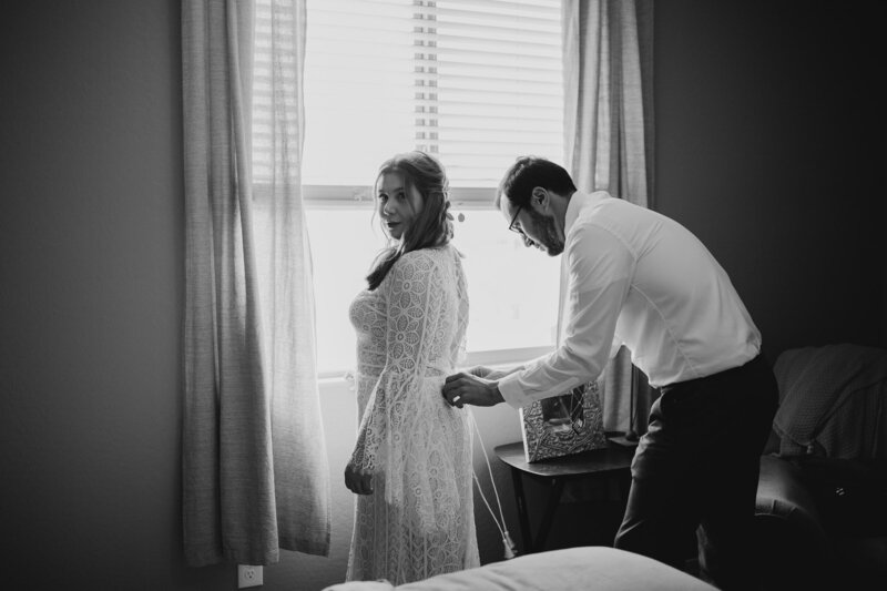 bride getting dressed in her lace boho wedding dress