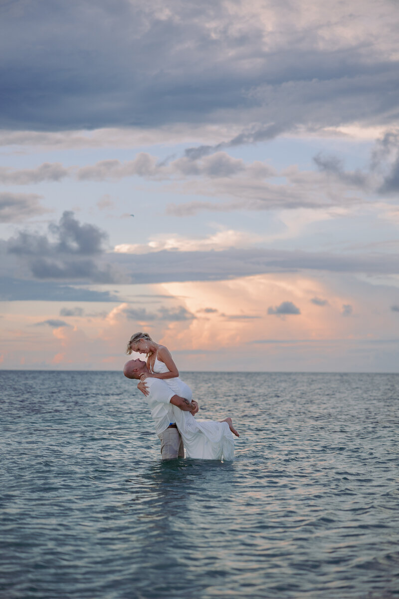 man and woman swinging small child between them while standing on the beach