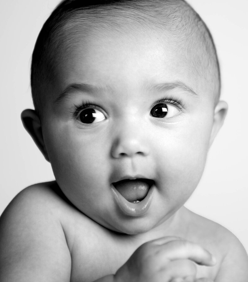 A baby making a funny face, captured in a playful black and white photo.