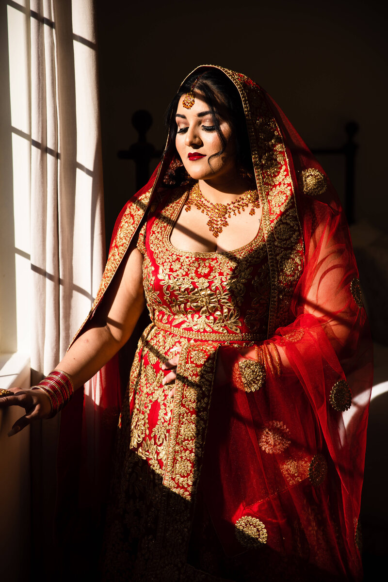 Indian bride at San Diego wedding, standing by window with eyes closed