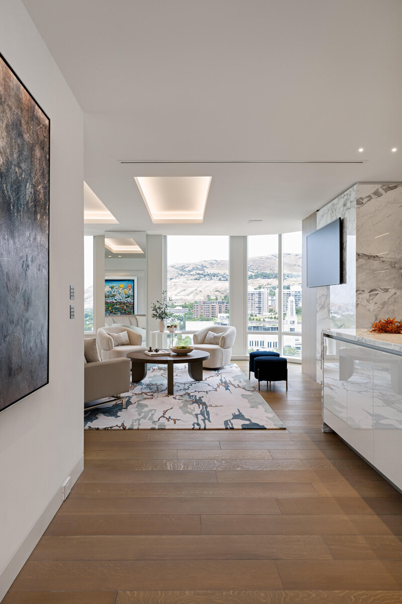 Wide shot of entrance into luxury apartment living room and kitchen with marble, custom lighting and blue accent details, designed by Sister Studio.