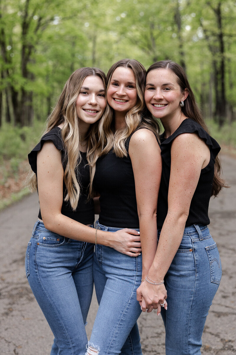 Adult sisters standing together hugging during a lifestyle family session. 