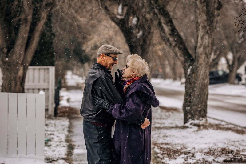 elderly couple dances on sidewalk in the snow