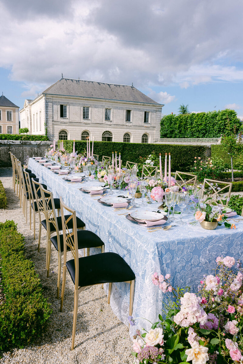 Reception table with tableware & silverware placed on it upon fine linens. Set up in the gardens of Chateau du grand luce for a wedding